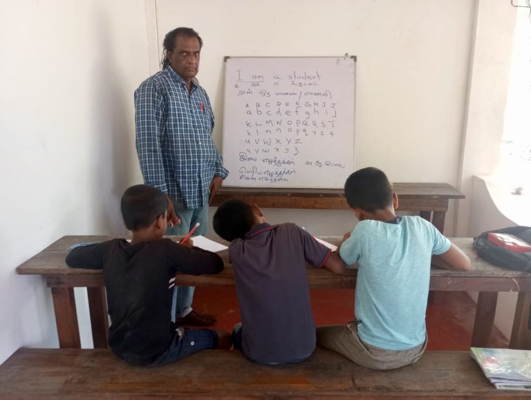 Elderly man teaches free english and sinahala classes to tamil students in sri lanka.