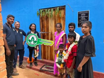rural family with new home, safe housing in Sri Lanka, family outside newly built house, Vanni Hope housing project, rural home construction, improved living conditions, community-supported housing, permanent home for family, children at new home, sponsored housing initiative