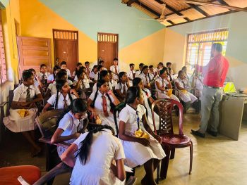 students attending drug awareness workshop, Vanni Hope community education project, rural school program in Trincomalee Sri Lanka, youth learning about drug prevention, teacher training session on drug awareness, community responsibility for student wellbeing, educational posters on drug-free living, group discussion with students and facilitators, empowering adolescents through life skills, interactive awareness session in rural library