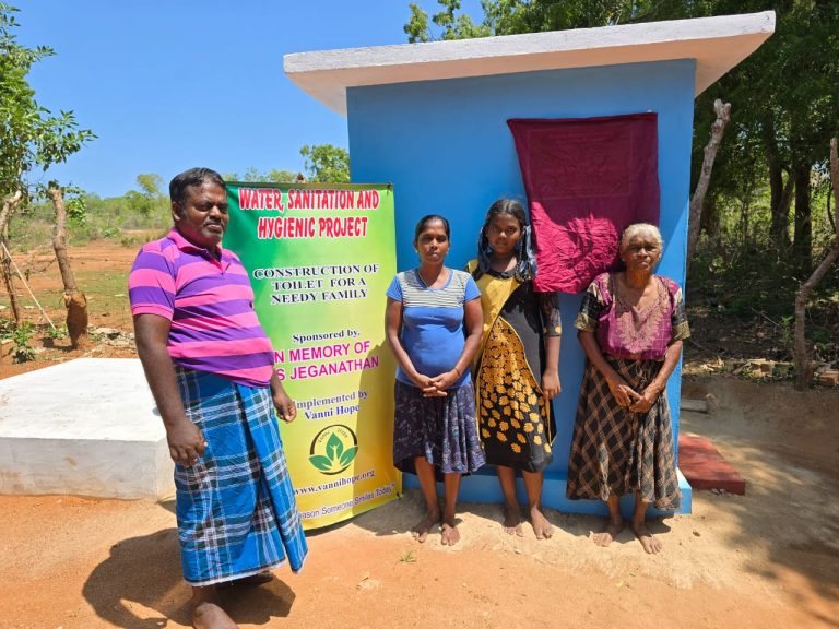 family photo in front of rural home Ampara, exterior of beneficiary house Pottuvil Sri Lanka, sanitation project proposal first page, toilet construction technical details page, septic tank construction diagram and notes, handwritten Tamil request letter for assistance, project cost breakdown table for toilet construction, sanitation support documentation Sri Lanka